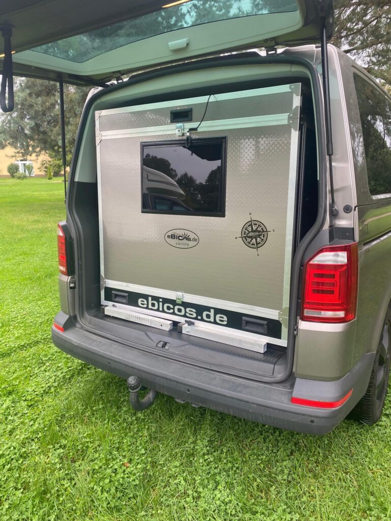 Eingeschobenes ebicos Schlafmodul im Heck eines VW Bus bei geöffneter Heckklappe